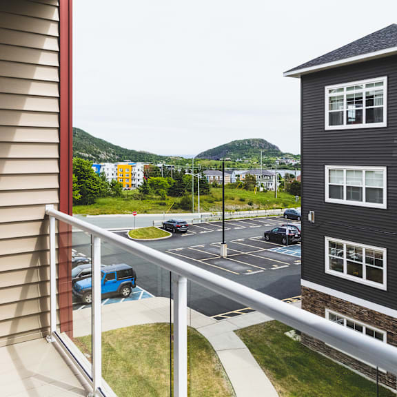 a balcony overlooks a parking lot and a mountain.