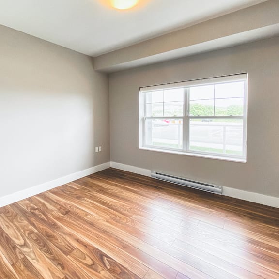 a room with a window and wooden flooring.