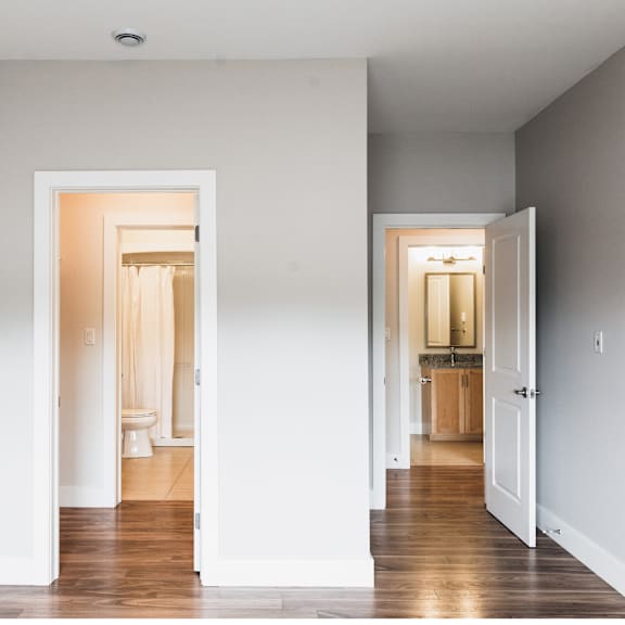 a hallway with two open doors leading to bathrooms.