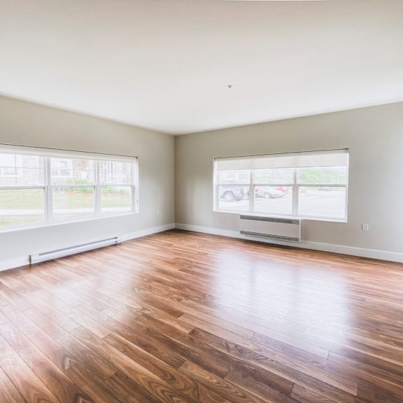 a room with wooden flooring and two windows.