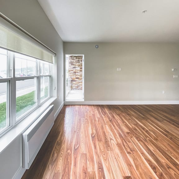 a room with wooden floors and a window overlooking a street.