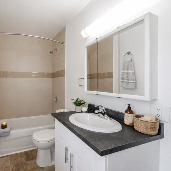 a bathroom with a white toilet, a sink, and a shower.