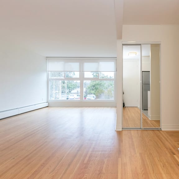 a room with wooden floors and a sliding glass door leading to a balcony.