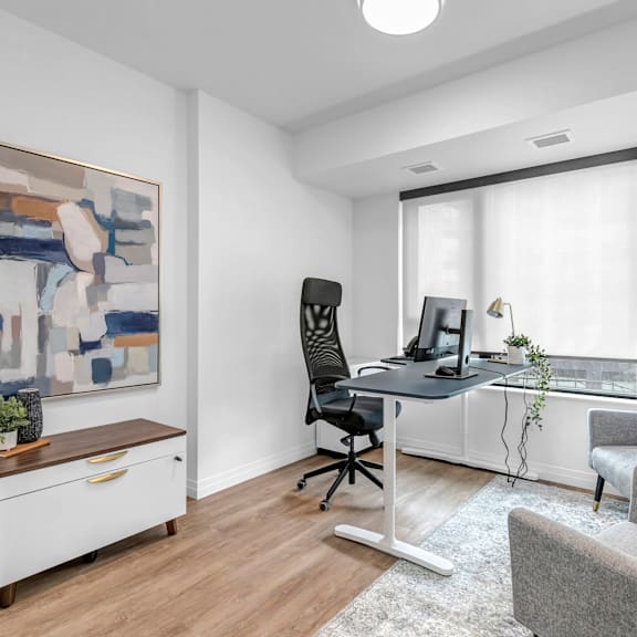 a modern home office with a desk, chair, and a painting on the wall.