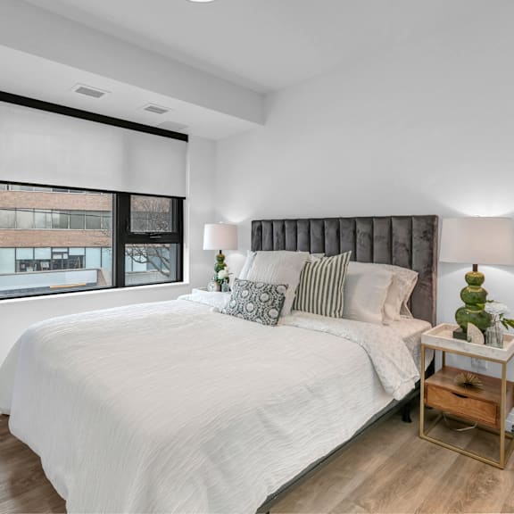 a bedroom with a large bed and a window with blinds.