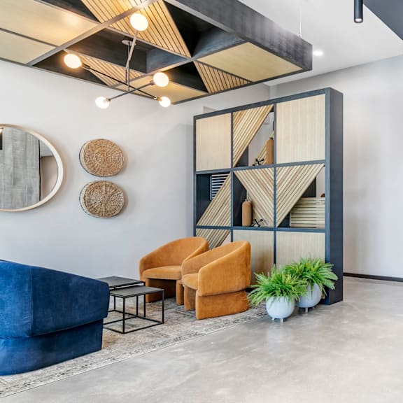 a modern living room with a blue velvet sofa, a wooden shelf, and a round mirror on the wall.