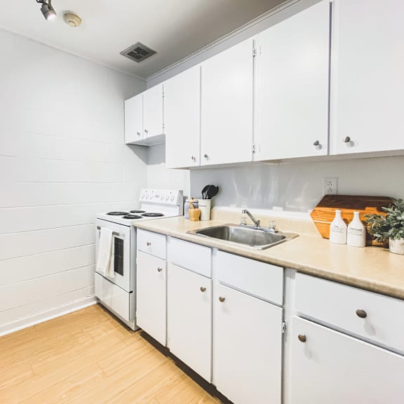 a kitchen with white cabinets and a wooden floor.