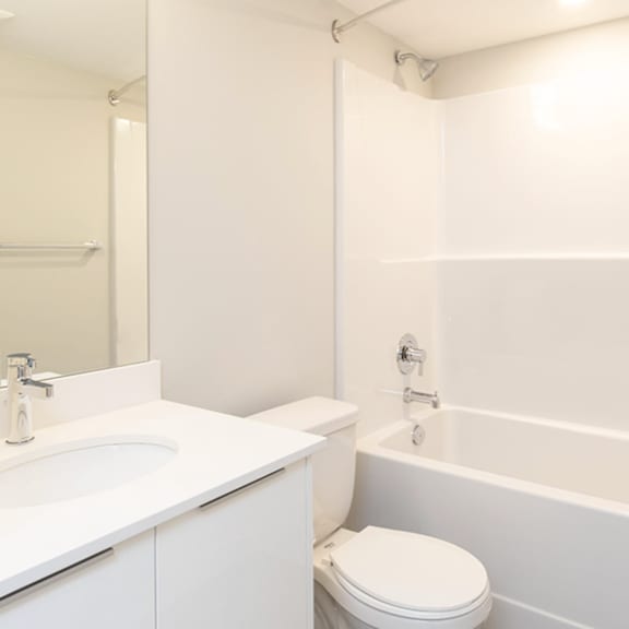 a white bathroom with a toilet, sink, and bathtub.