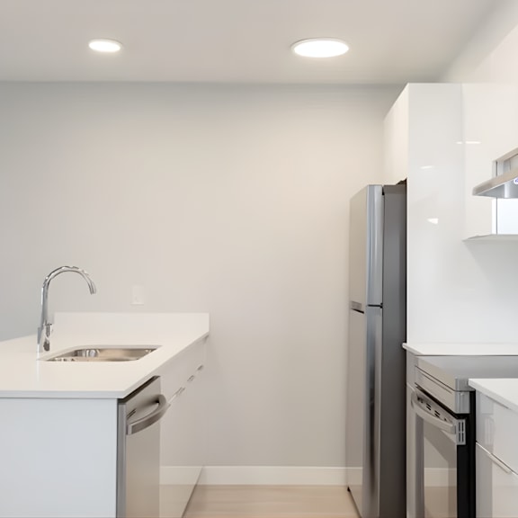 a modern kitchen with a white countertop and stainless steel appliances.