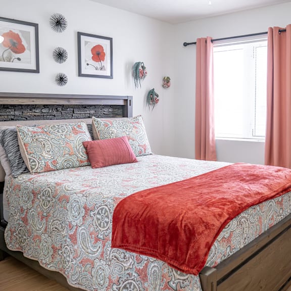 a bed with a red blanket and a grey and red patterned duvet cover.