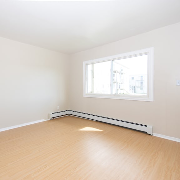 empty room with a window and a radiator on the wall.
