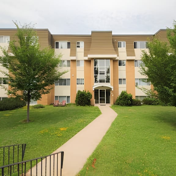 a building with a brown roof and tan walls with a walkway in front.