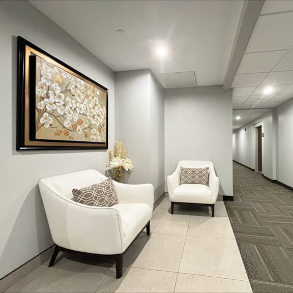 a hallway with two chairs and a painting on the wall.