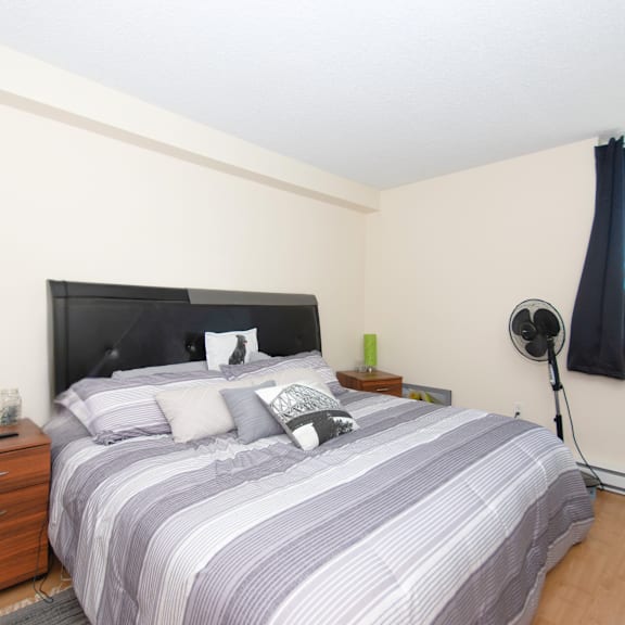 a bedroom with a bed, nightstand, and lamp.