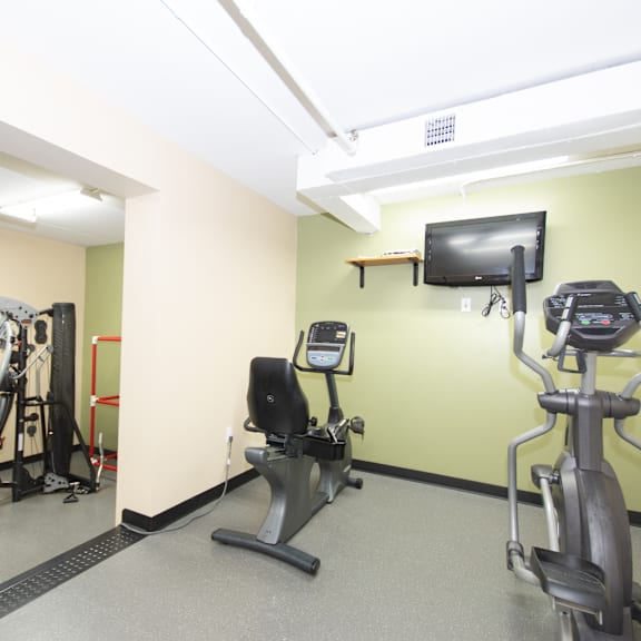 a gym with a treadmill, exercise bike, and a television.