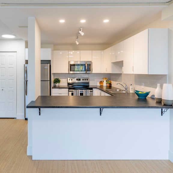 a modern kitchen with a black countertop and white cabinets.