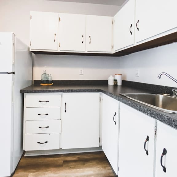 a kitchen with white cabinets and a black countertop.