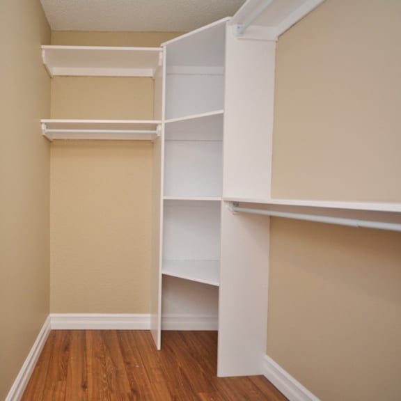 a white shelving unit in a room with beige walls and wooden floors.