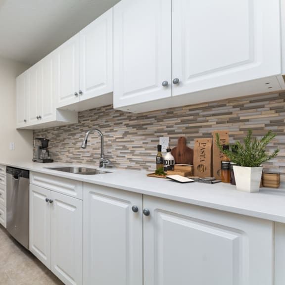 a kitchen with white cabinets and a stone backsplash.