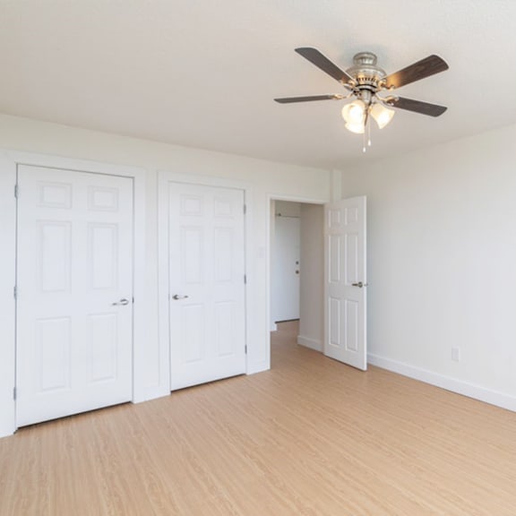 a room with a ceiling fan and three doors.