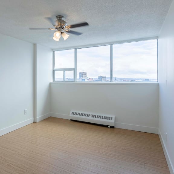 a room with a ceiling fan and a window overlooking a cityscape.