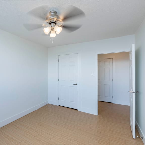 a room with a ceiling fan and two doors.