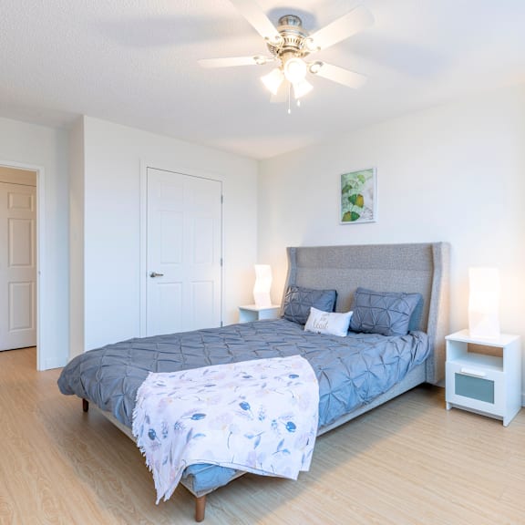 a bedroom with a bed, a ceiling fan, and a nightstand.