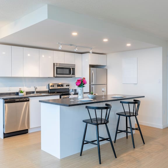 a modern kitchen with a black countertop and white cabinets.