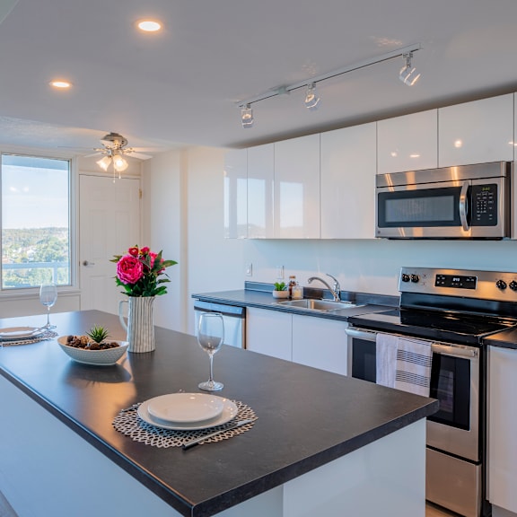 a modern kitchen with a black countertop and white cabinets.