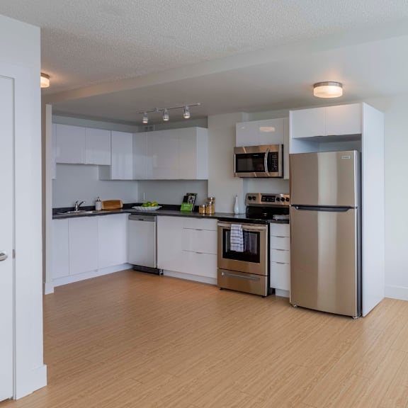 a kitchen with white cabinets and a wooden floor.