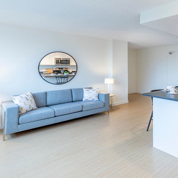 a modern living room with a grey sofa and a round mirror on the wall.