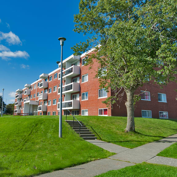 a red brick apartment building with a tree in front.