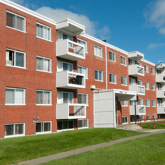 a red brick apartment building with white balconies and doors.