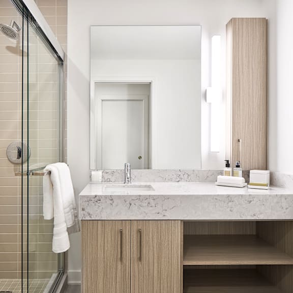 a white towel hangs on a glass shower door in a modern bathroom.