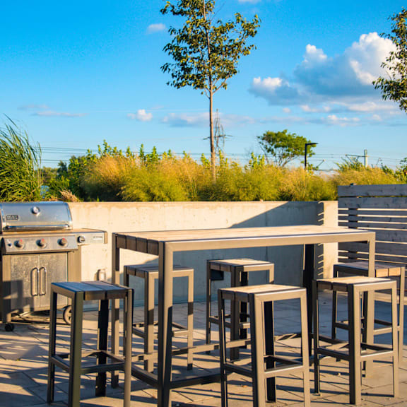 a set of outdoor bar stools are in front of a concrete counter.