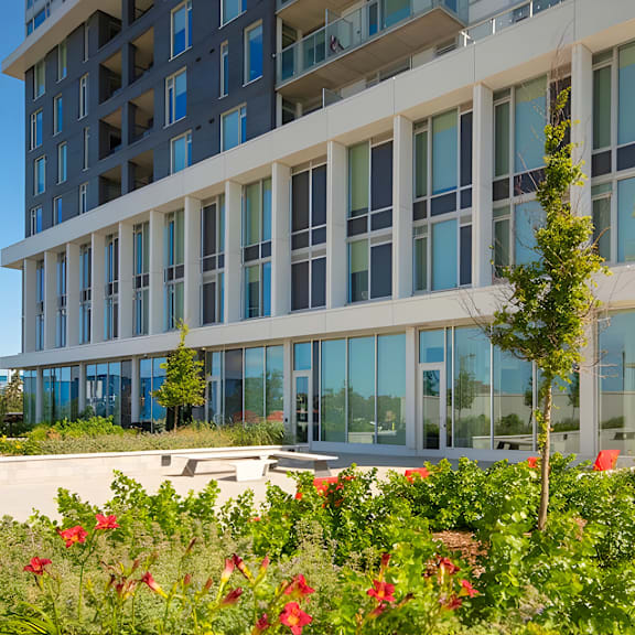 a modern building with a lot of windows and some plants in front.