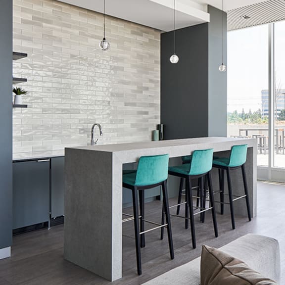 a modern kitchen with a bar area and green chairs.