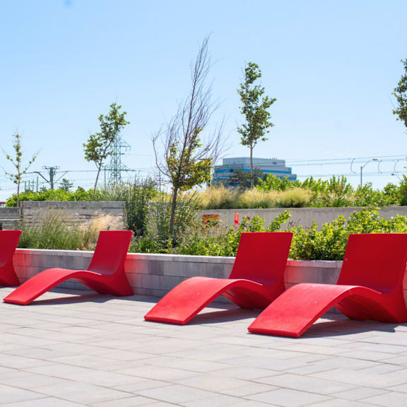 four red chairs are lined up on a patio.