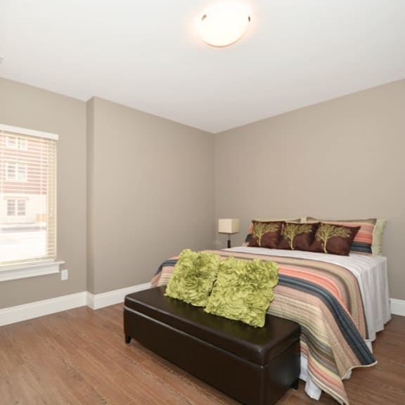 a bedroom with a bed, a bench, and a window.
