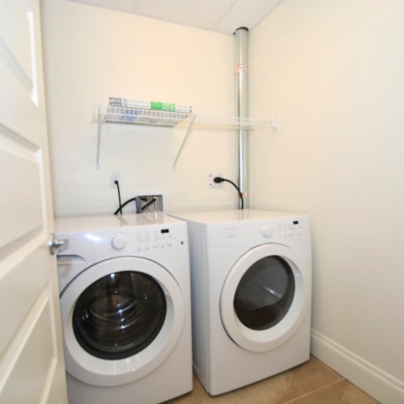 two white front load washing machines in a small laundry room.