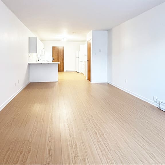a spacious room with wooden flooring and white walls.