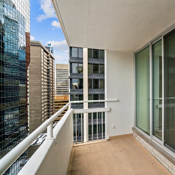 a balcony with a white railing and glass doors overlooks a cityscape.