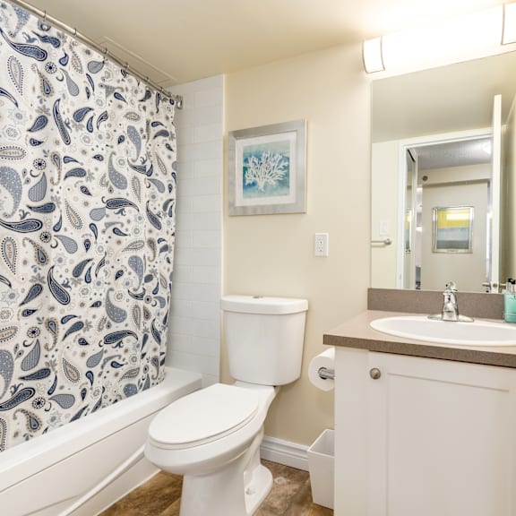 a bathroom with a toilet, sink, and shower curtain.