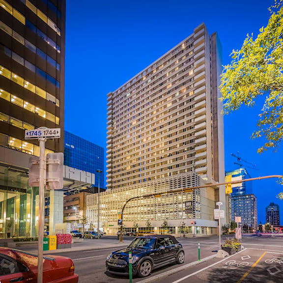 a city street at dusk with cars and tall buildings.