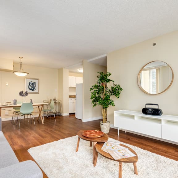 a living room with a white sofa, a wooden coffee table, and a round mirror on the wall.