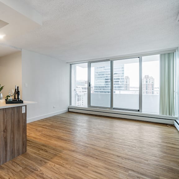 a spacious room with wooden flooring and a large window overlooking a cityscape.