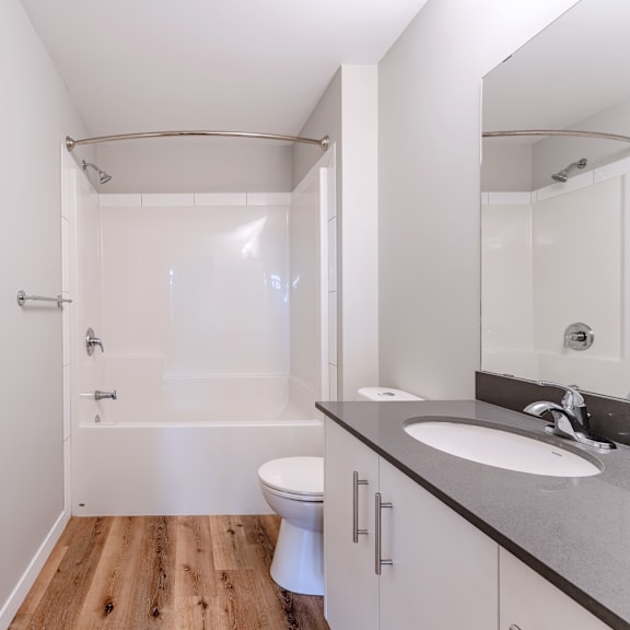 a white bathroom with a wooden floor and a white toilet.