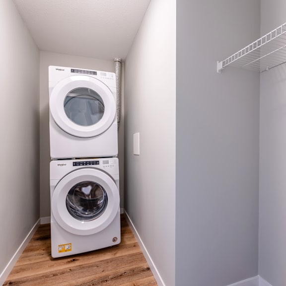 a white dryer and washer are stacked on top of each other in a small laundry room.