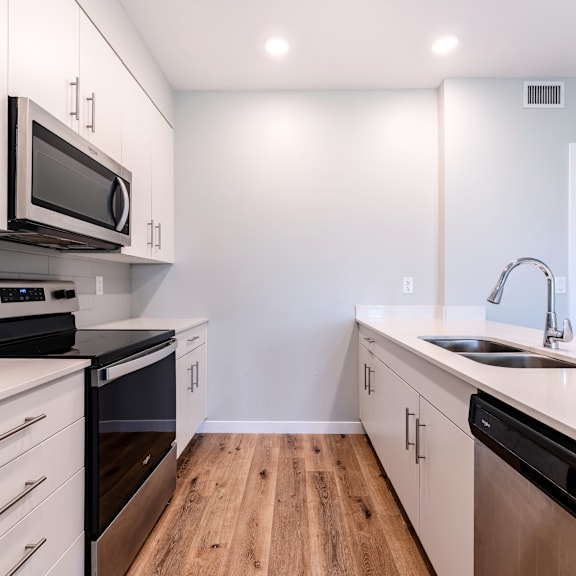 a kitchen with white cabinets and black appliances.
