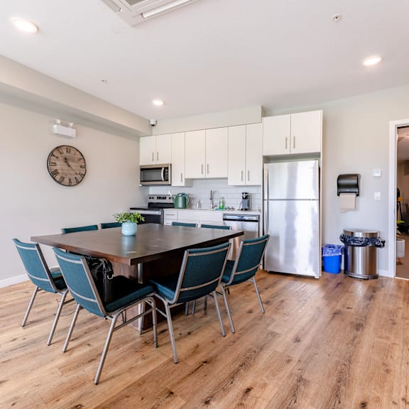 a kitchen with a table and chairs in the foreground and a refrigerator in the background.
